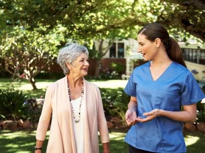 An image of a Home Health Aid and Patient Walking Outside