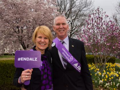 White Couple with Sign and Flowers Outside
